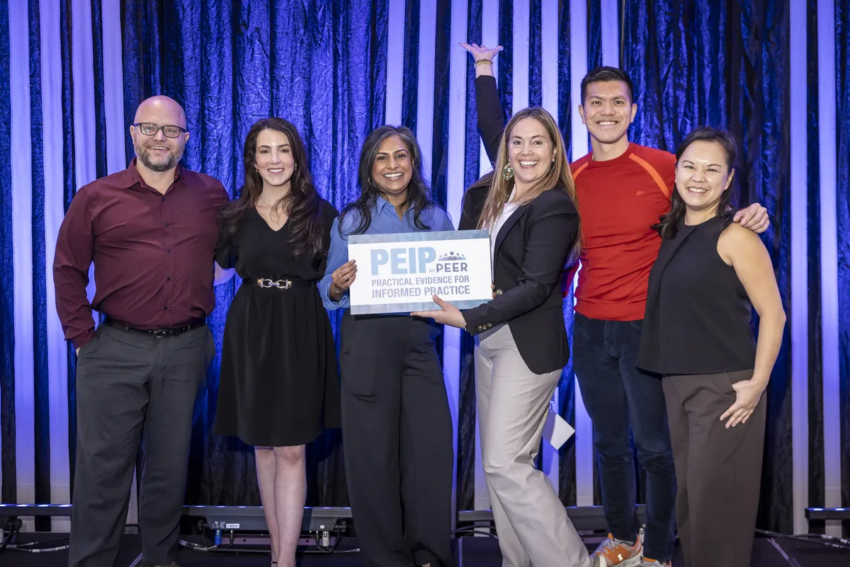 Members of the PEIP by PEER 2026 team on stage holding a PEIP by PEER sign